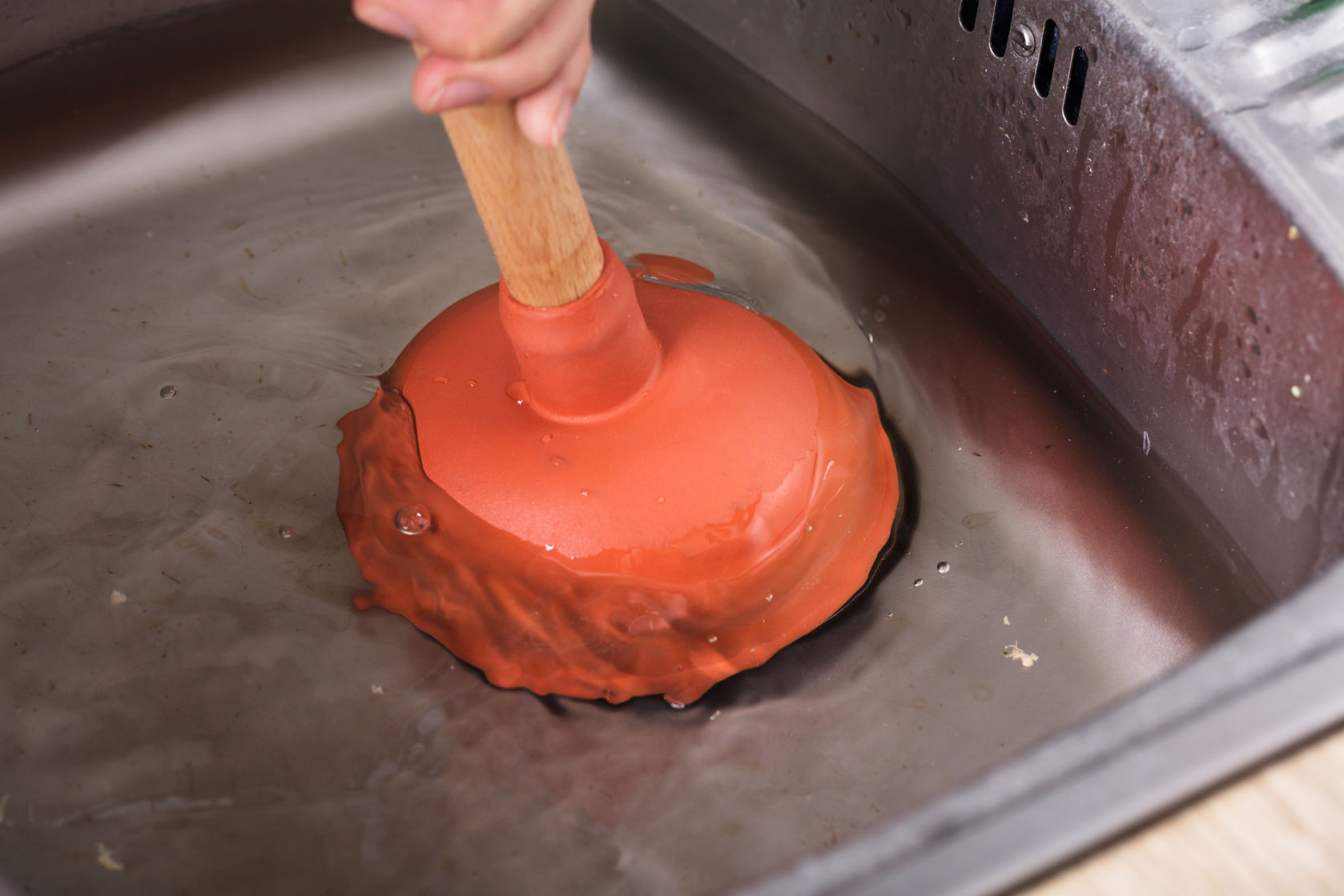 94289518 - close-up of a person cleaning sink filled with water with cup plunger